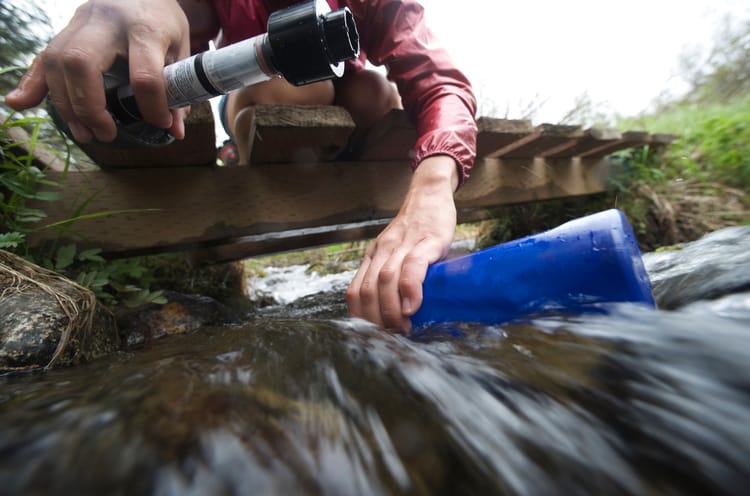 a female hiker filling up her water bottle to showcase portable water filter rv options